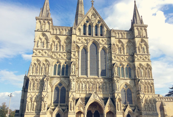 The front of Salisbury Cathedral, complete with very intricate carvings and many windows. 