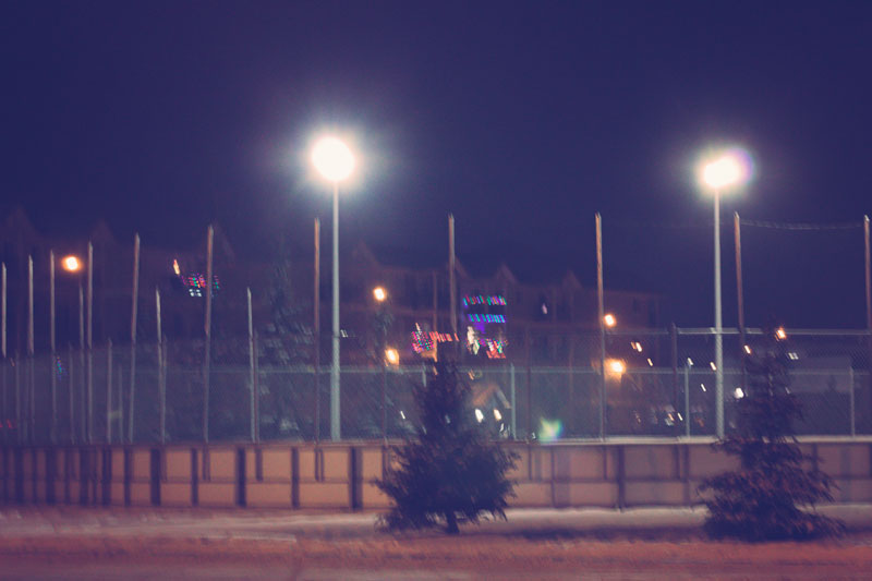 A neighbourhood ice rink at night with two spotlights on.