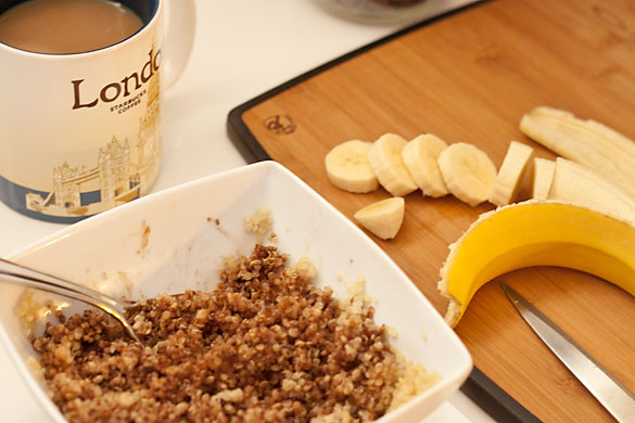 Quick, easy, healthy breakfast including quinoa with melted chocolate chips blended in and sliced banana on a chopping board. A cup of coffee is included in the photo.