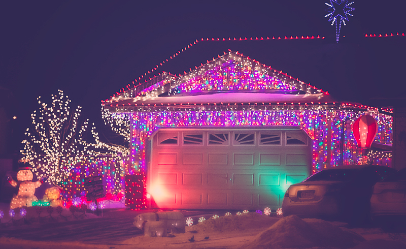 A house with a garage completely covered in rainbow coloured christmas lights. 