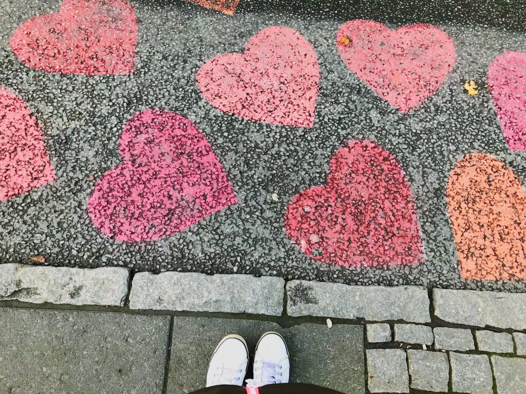 A road in Iceland with pink, red, and orange hearts painted on them. 
