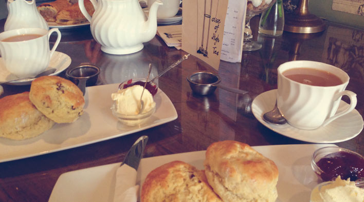 A traditional English High Tea at a salon in England featuring tea, crumpets, whipped cream and jam. 