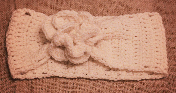 A cream-coloured crocheted headband with a crocheted flower.