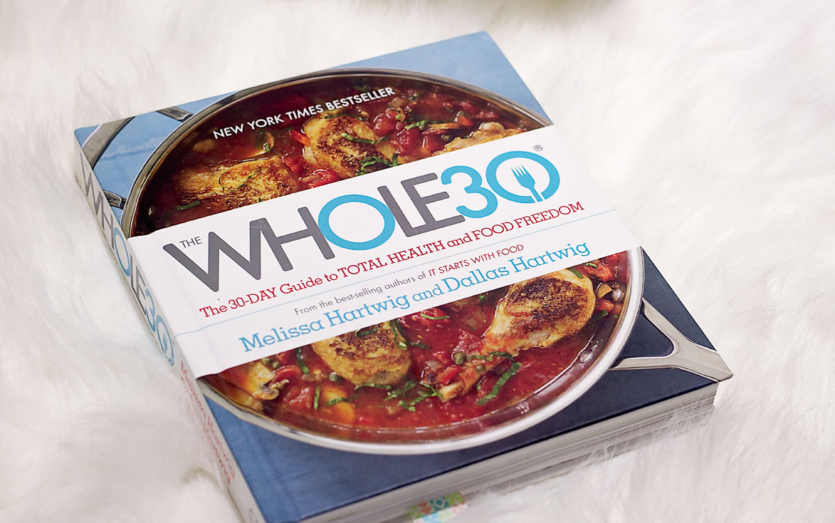 The front cover of the whole30 book I used to follow my whole 90. It features a deep pan with a red coloured soup filled with vegetables.