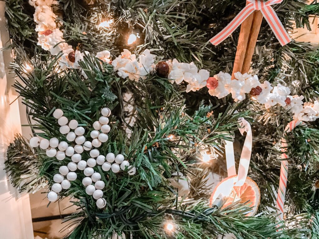 A close up of a wooden bead snowflake ornament with a string of popcorn garland. 